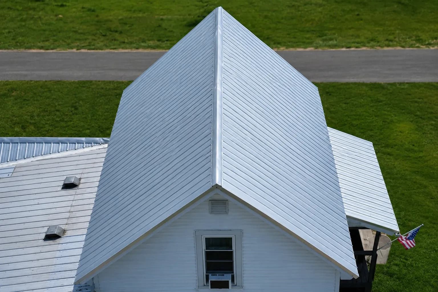 Aerial view of a white standing-seam metal roof on a farmhouse
