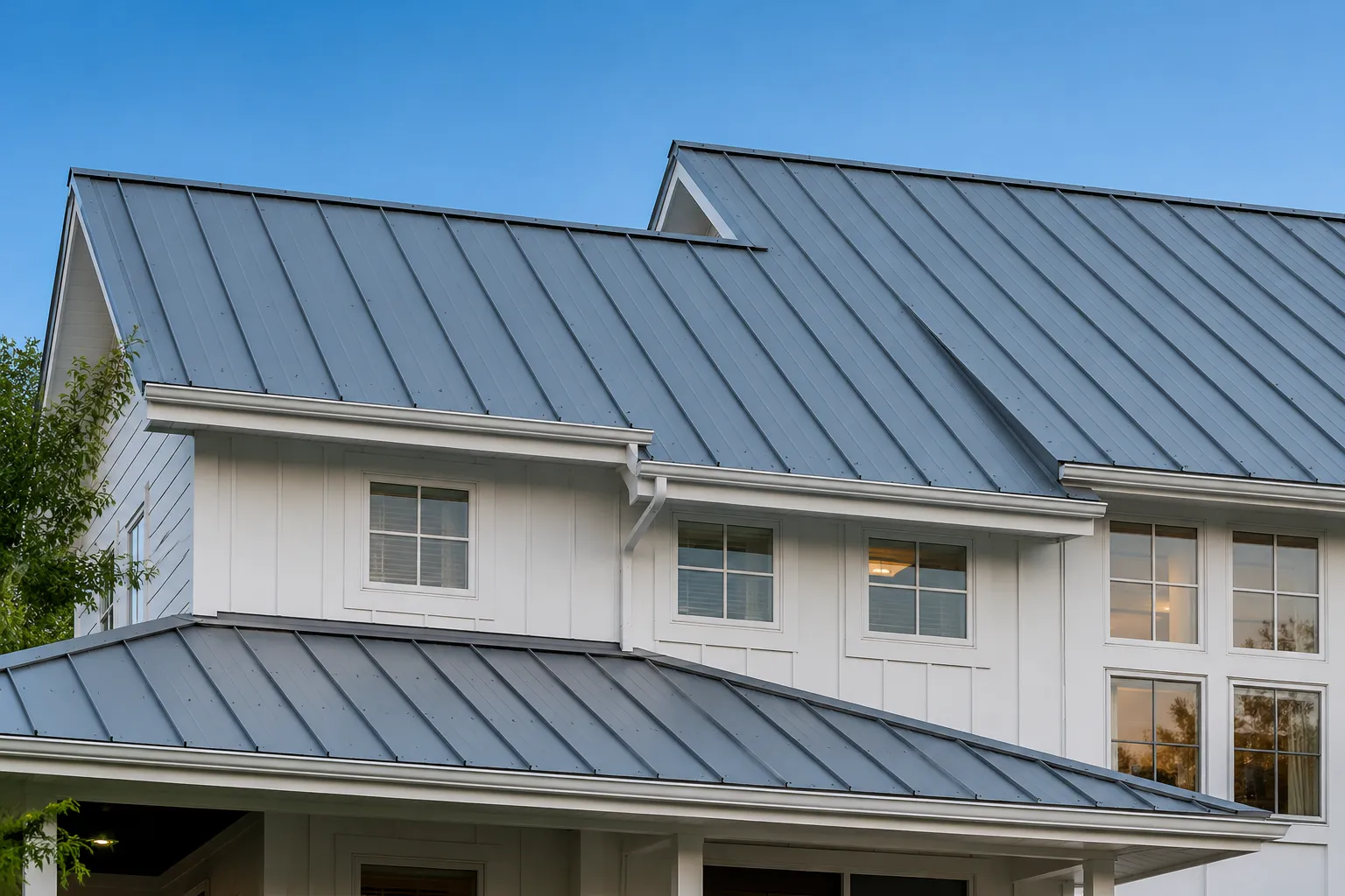 A charcoal standing-seam metal roof on a modern farmhouse at dusk