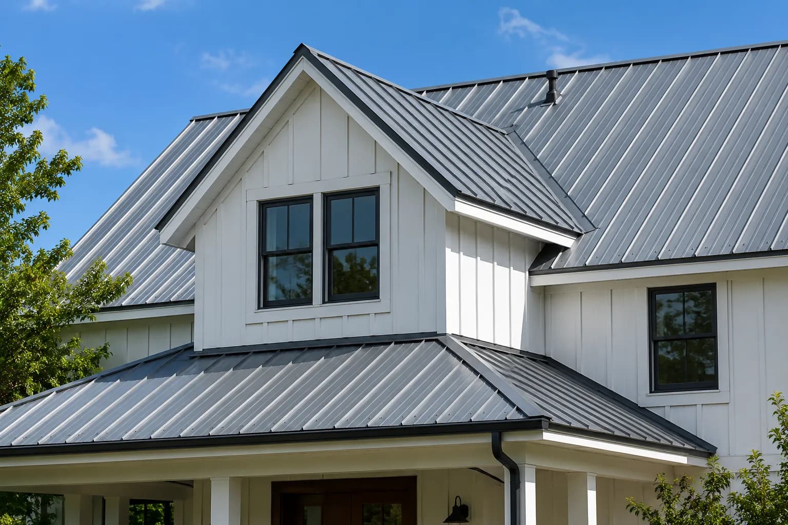 A dark standing-seam metal roof on a white board-and-batten farmhouse