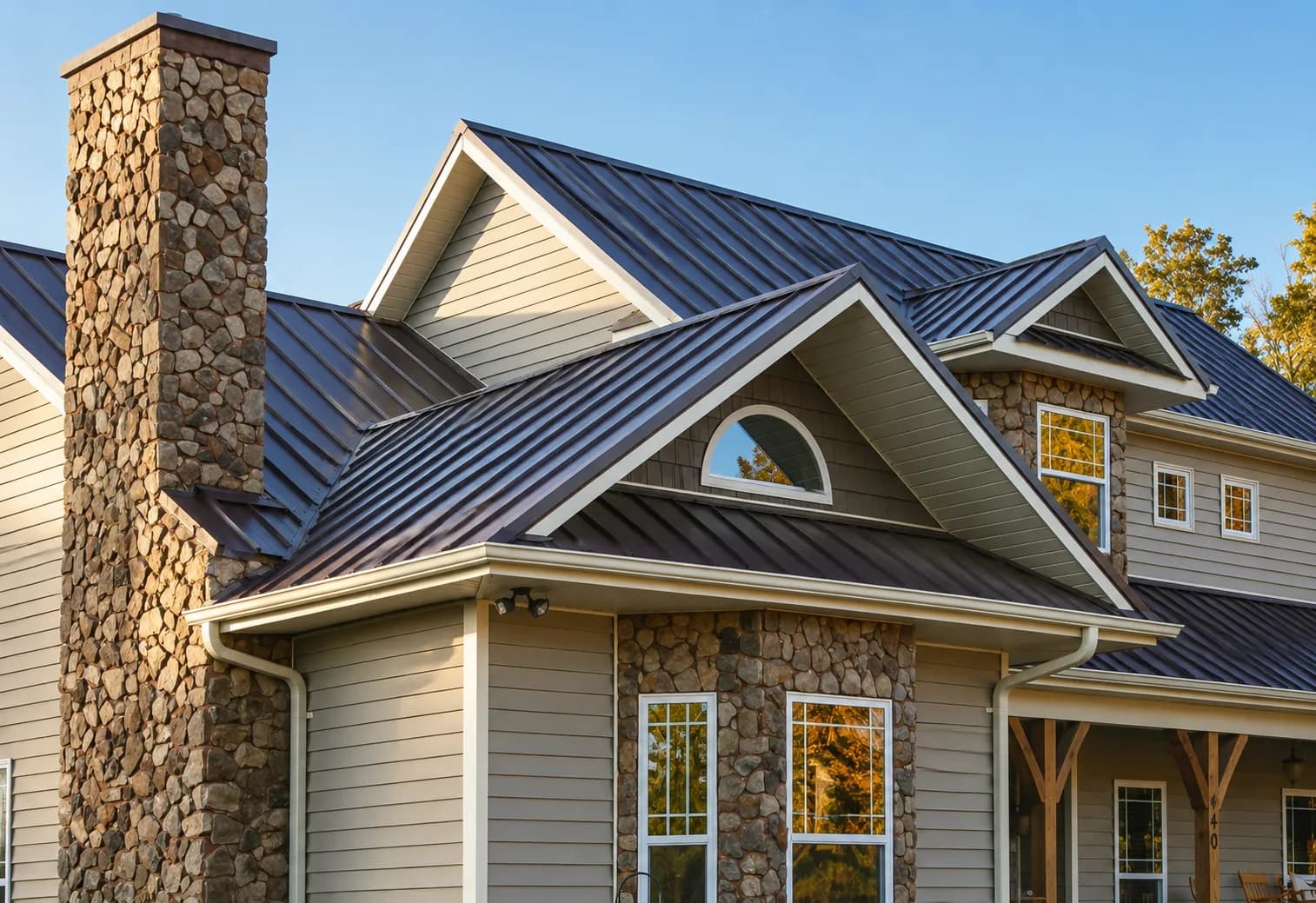 A bronze standing-seam metal roof on a home with a stone chimney